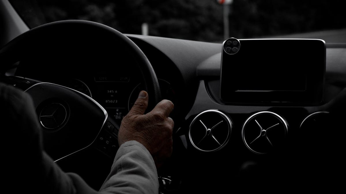 Driver holding a car steering wheel — steering wheel lock vs brake pedal lock