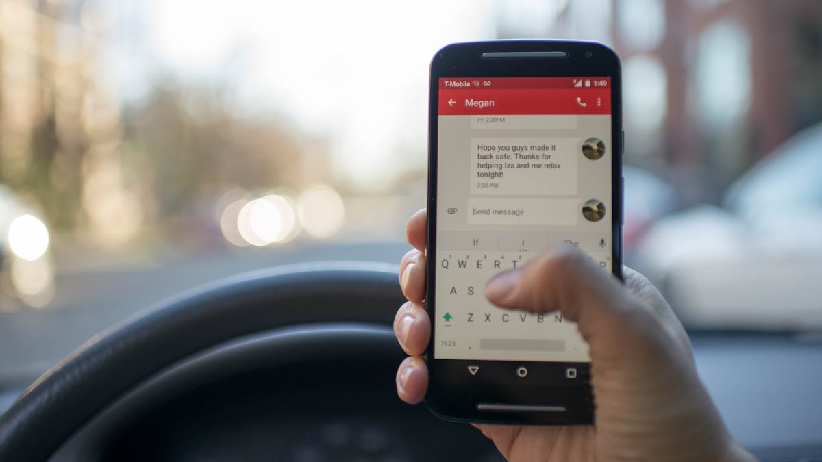 Person using a smartphone inside a car — best Bluetooth car anti-theft device