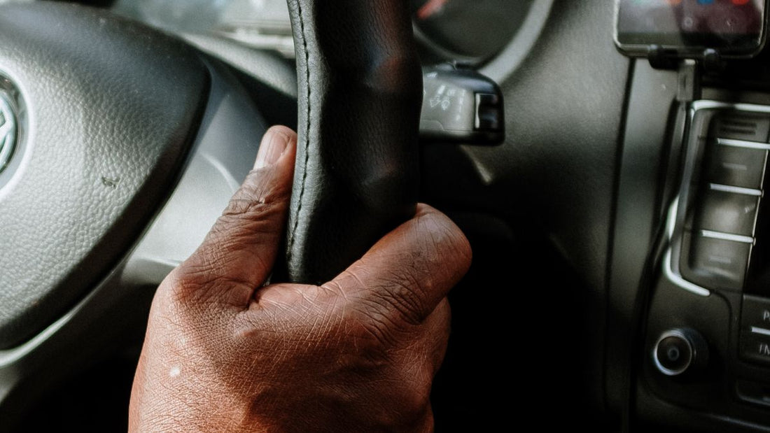 Person holding a black steering wheel — is a brake pedal lock worth it
