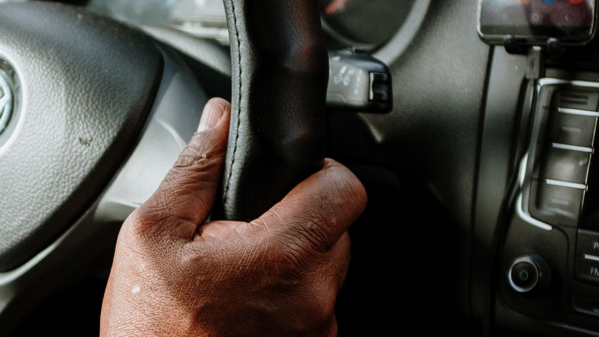Person holding a black steering wheel — is a brake pedal lock worth it